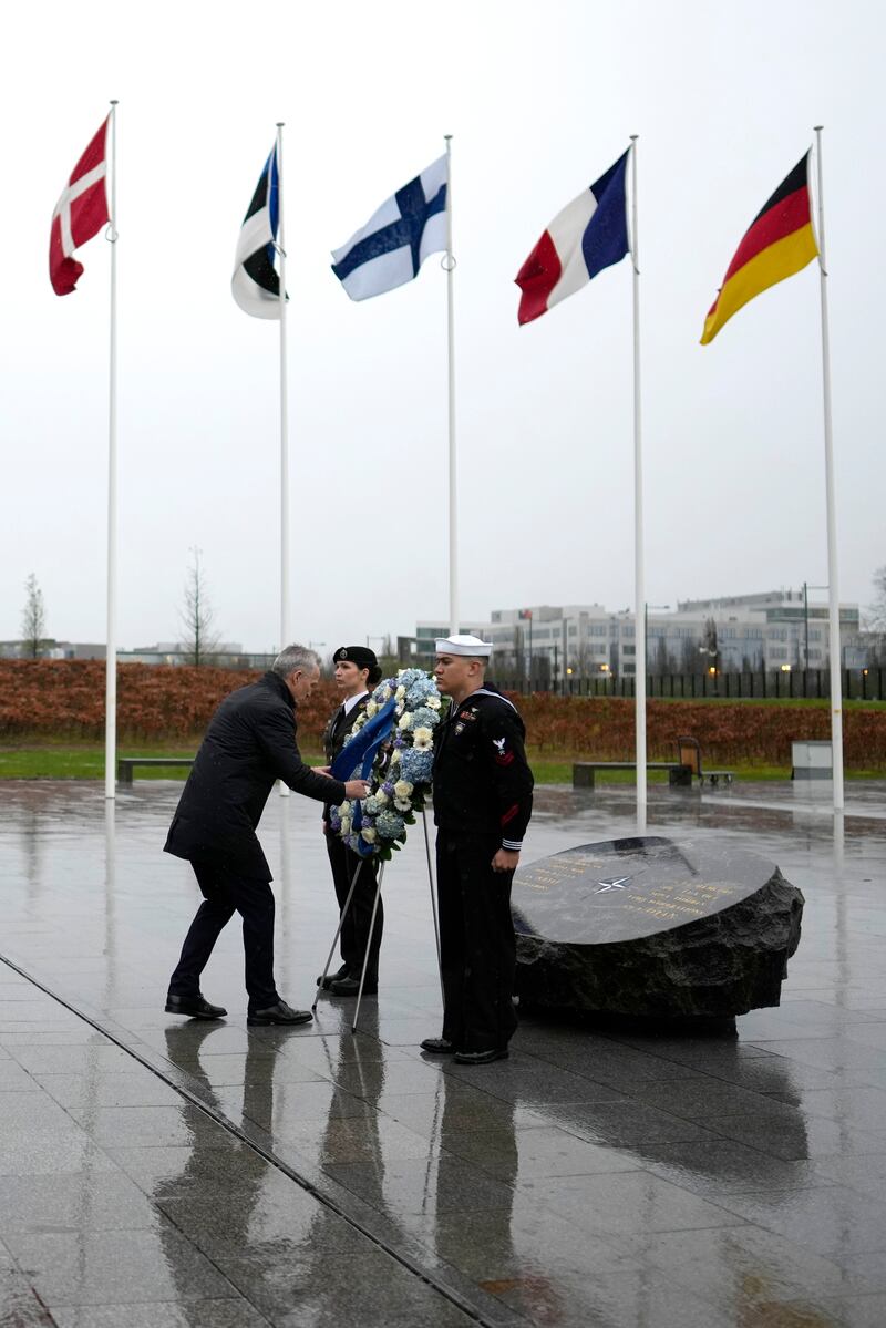Nato secretary general Jens Stoltenberg adjusts a ribbon during a wreath-laying ceremony at Nato headquarters in Brussels (Virginia Mayo/AP)