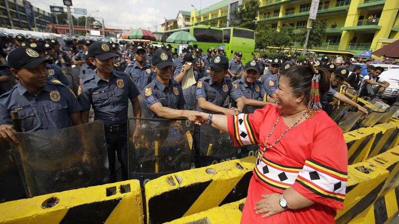Filipino activist and director Mae Paner shakes hands with policemen blocking the road as she joins a rally with thousands of other activists and supporters of Philippine President Rodrigo Duterte near the gates of the House of Representatives in suburban Quezon city, north of Manila. Picture by Aaron Favila, Associated Press