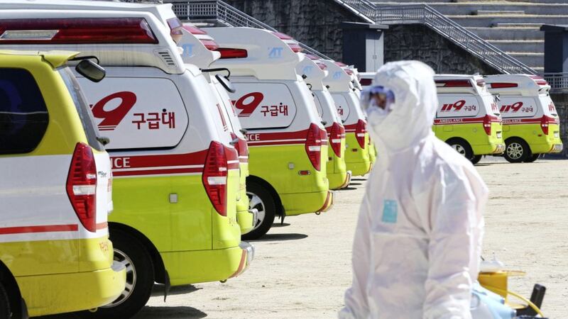 Ambulances gather as a member of paramedic wearing protective gears walk in Daegu, South Korea. Picture by Kim Hyun-tai/Yonhap/AP 