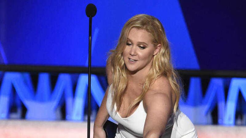Amy Schumer hands her shoe to Tracee Ellis Ross as she accepts the award for best actress in a comedy for Trainwreck at the 21st annual Critics&#39; Choice Awards at the Barker Hangar on Sunday in Santa Monica, California PICTURE: Chris Pizzello/Invision/AP 