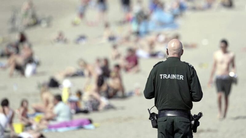  A PSNI officer views the crowd enjoying the Sunday sunshine at Ballyholme beach, Bangor, Co Down. Picture by Stephen Davison. 