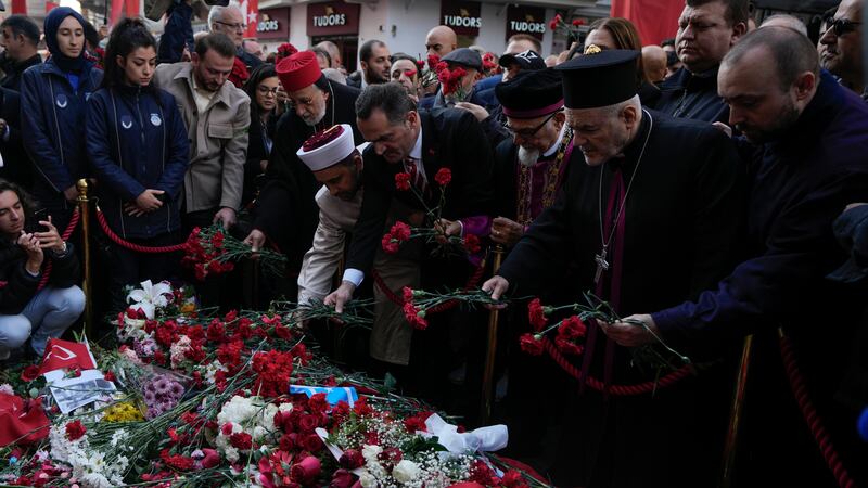 Representatives of the Turkish communities put flowers over a memorial placed on the spot of an explosion on Istanbul’s popular pedestrian Istiklal Avenue in 2022 (Khalil Hamra/AP)