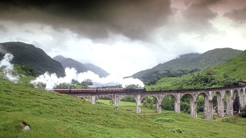 The Jacobite Express steam train puffs over the Glenfinnan Viaduct in the Scottish Highlands 