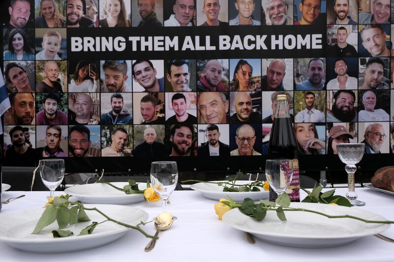 Pictures of hostages kidnapped during the October 7 Hamas attack in Israel are placed by a table set during a protest outside the International Court of Justice (Patrick Post/AP)