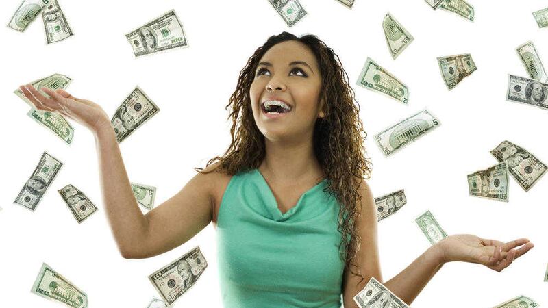 Stock image of woman standing with open arms amidst falling money 