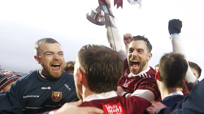 Neil McManus brings the trophy back to his Cushendall team-mates.