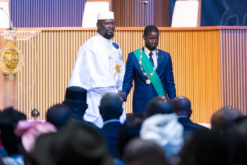 Bassirou Diomaye Faye, right, greets Guinea’s interim president Mamadi Doumbouya during his swearing in ceremony (Sylvain Cherkaoui/AP)