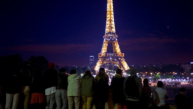 Tourists look at the illuminated Eiffel Tower in Paris (Thibault Camus/AP, File)