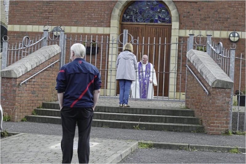 Fr Paddy McCafferty resumes hearing confessions while observing social distancing though the locked gates of Corpus Christi Church in Ballymurphy, West Belfast.Picture by Hugh Russell. 