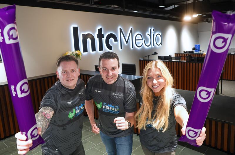 Connor Brennan, Neil Loughran and Amy McGuckan posing in the IntoMedia offices in their black McKeever Sportswear jerseys ahead of the Belfast City Marathon