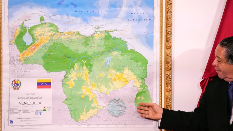 Hermann Escarra, chairman of the Special Commission for the Defence of Guyana Essequibo, stands next to Venezuela’s new map that includes the Essequibo territory (Matias Delacroix/AP)