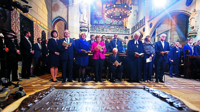 German Chancellor Angela Merkel, center, left, president Frank-Walter Steinmeier, right, and president of Germany's parliament Bundestag Wolfgang Schaeuble, center right, attend ceremonies for the 500th anniversary of the Reformation in front of the grave of Martin Luther at the Castle Church in Wittenberg, Germany, on Tuesday. Picture by Hannibal Hanschke, Pool via Associated Press&nbsp;