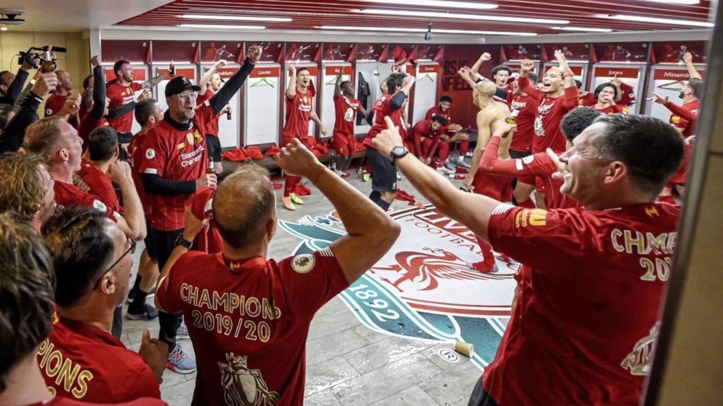 Liverpool FC players and managerial team, including Jurgen Klopp (left of centre with baseball cap), celebrate their historic Premier League win in July in a scene from The End Of The Storm