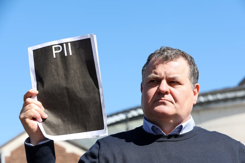 Paddy Fox whose parents Charlie and Tess Fox were murderedin 1992 holds up a Public Interest Immunity (PII) certificate  at Belfast Laganside Court. PICTURE: MAL MCCANN
