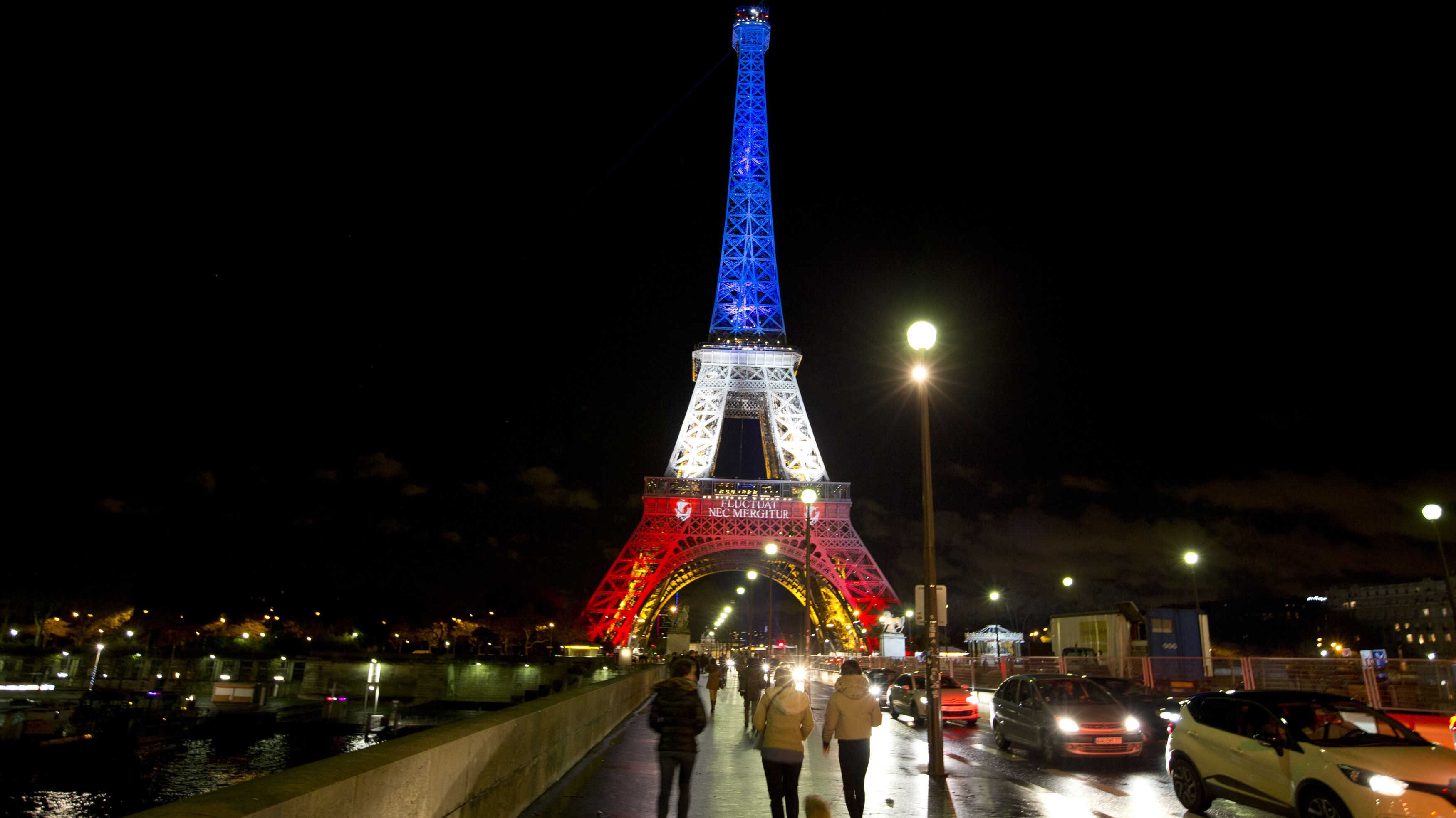 People walk towards the illuminated Eiffel Tower in the French national colors red, white and blue in honor of the victims of the attacks in Paris. Picture by Peter Dejong, AP 