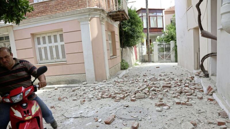 A man with his motorcycle passes next to a damaged house after an earthquake in the village of Plomari. Picture by Manolis Lagoutaris/InTime News via Associated Press. 