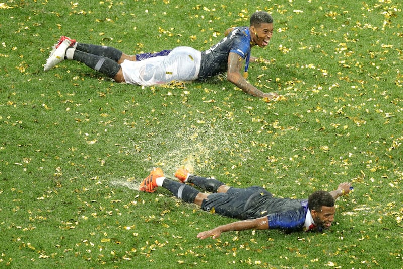 France's Presnel Kimpembe (top) and Samuel Umtiti celebrate on the wet grass after winning the FIFA World Cup Final at the Luzhniki Stadium in Moscow&nbsp;