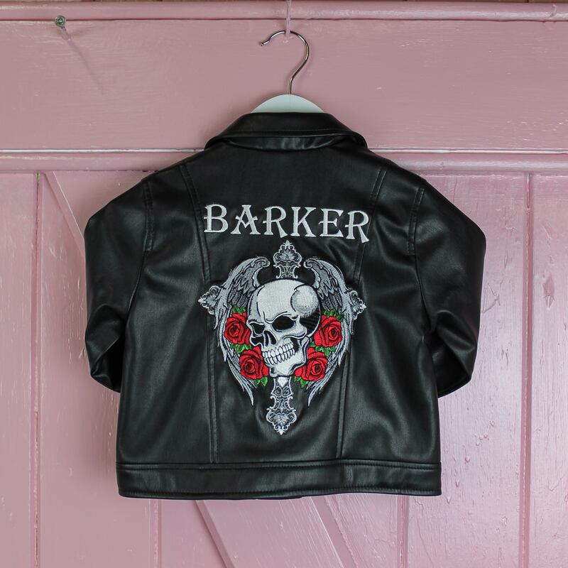 Baby sized leather jacket. The is a skull on the back of the jacket with floral embroidery around it.
