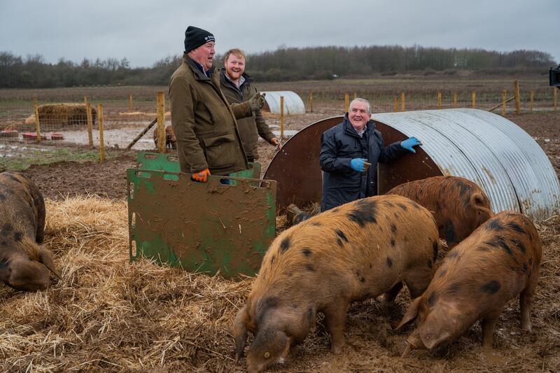 Jeremy Clarkson and Kaleb Cooper standing laughing in a pig sty
