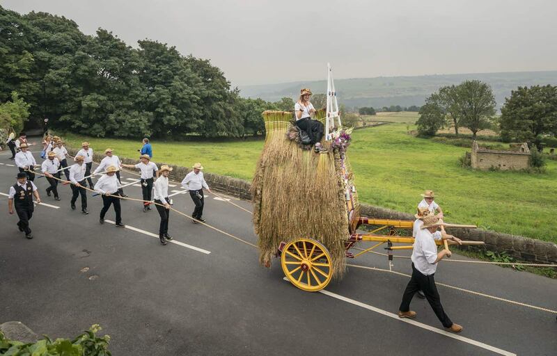 Men dressed in Panama hats, white shirts and clogs pull a 16ft-high thatched rush cart carrying a woman on top, during the Sowerby Bridge Rushbearing Festival in West Yorkshire