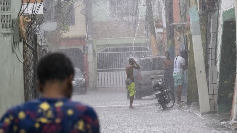 A man stands under a roof drain as rain from Tropical Storm Franklin falls on Santo Domingo, Dominican Republic (Ricardo Hernandez/AP)