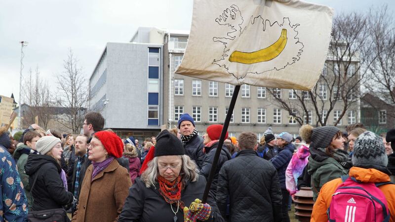A woman holds a banner and protests with others in front of Parliament building in Reykjavik, Iceland. Picture by David Keyton, Associated Press&nbsp;