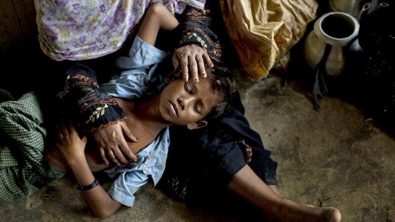 A Rohingya woman comforts her exhausted son as they take shelter inside a school after having just arrived from the Burma side of the border at Kutupalong refugee camp in Bangladesh PICTURE: Bernat Armangue/AP 
