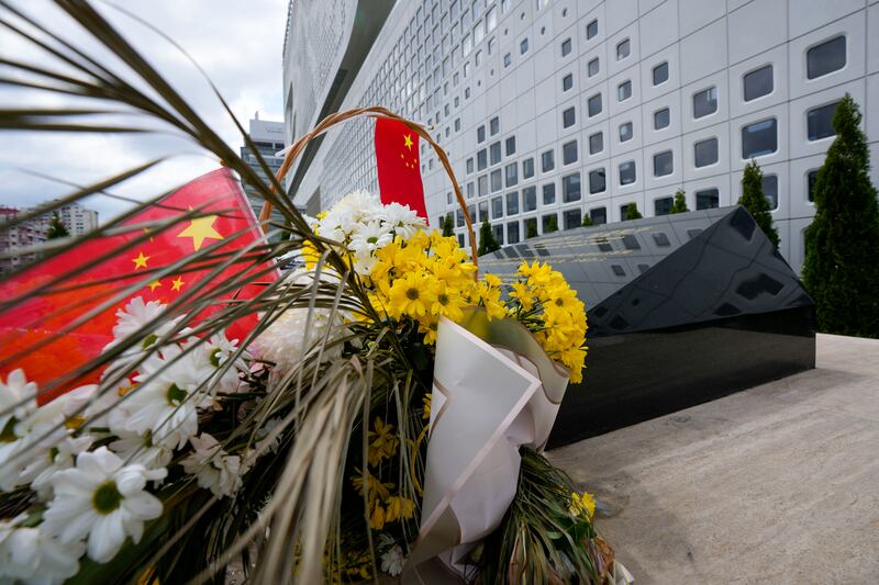 A Chinese flag is placed near flowers on a monument at the site of a former Chinese Embassy in Belgrade, Serbia (Darko Vojinovic/AP)