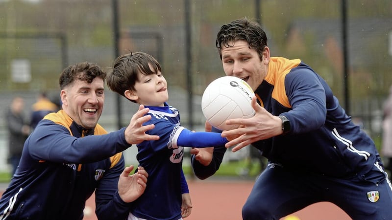 Antrim footballers Jack Dowling (right) and Ryan Murray teach young Ruairi McAreavey of Christ the Redeemer Primary School some ball catching skills at the school Picture: Mark Marlow 