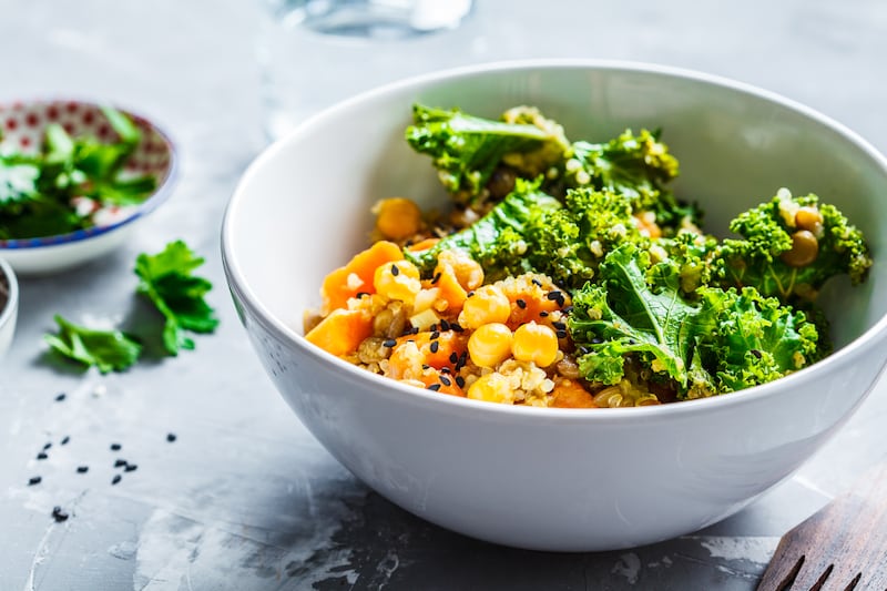 Vegan stew with chickpeas, sweet potato and kale in a white bowl