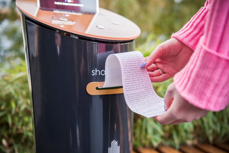 A woman uses a short story vending machine at Canary Wharf