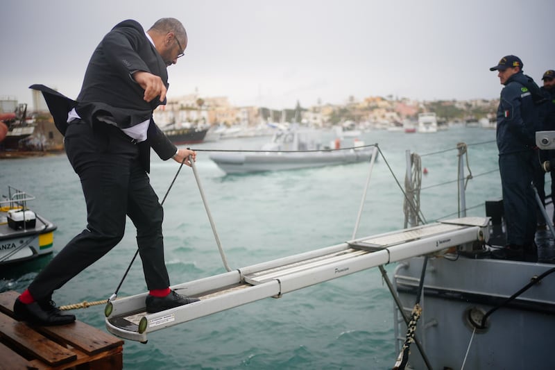 Mr Cleverly climbs on to a Guardia di Finanza police boat in Lampedusa Port
