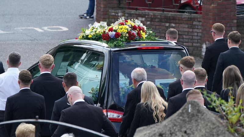 Mourners walk beside the hearse 