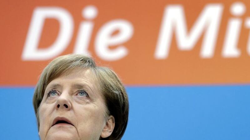 German Chancellor Angela Merkel looks up during a press conference after a party meeting at the headquarters of the German Christian Democratic Party (CDU) in Berlin, Germany on Monday, a day after the elections in the German state of Saarland. Slogan in the background reads &#39;The Centre&#39; PICTURE: Michael Sohn/AP 