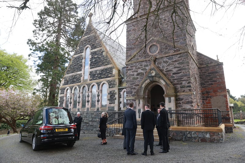Mourners gather as the hearse carrying the coffin of former BBC Northern Ireland political editor Stephen Grimason, arrives for his funeral mass at Drumbeg Parish Church in Dunmurry, Belfast