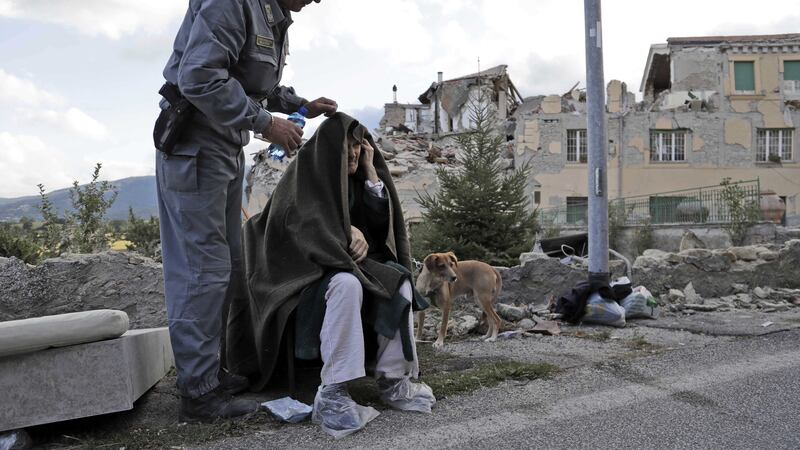 &nbsp;An elderly man is given assistance as collapsed buildings are seen in the background following an earthquake, in Amatrice, Italy. (AP Photo/Alessandra Tarantino)