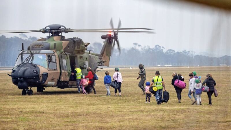 People boarding a helicopter as the fire-ravaged community of Mallacoota is evacuated. Picture by Corporal Nicole Dorrett/ADF/AP 