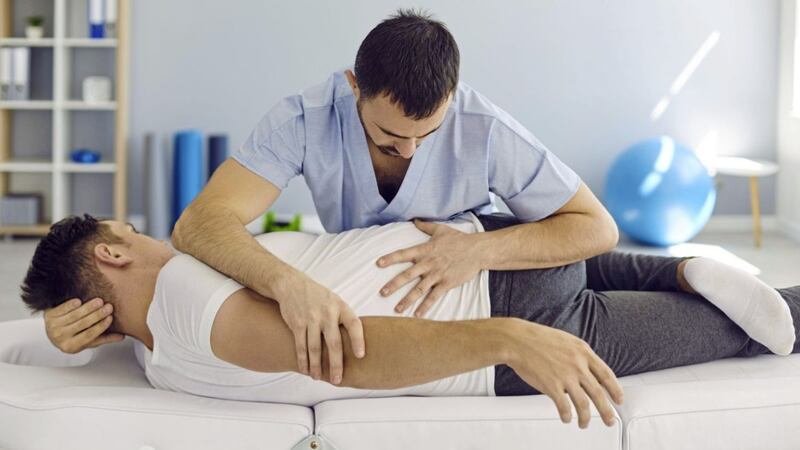 An osteopath working on a patient&#39;s back. Months of working from home, often at makeshift desks, has seen a rise in neck and back complaints 