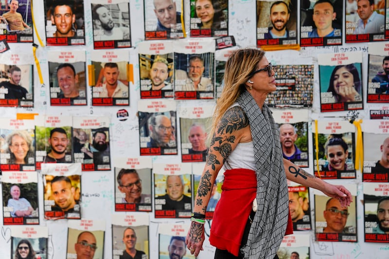 A woman walks past pictures of hostages in Tel Aviv, Israel (Ariel Schalit/AP)