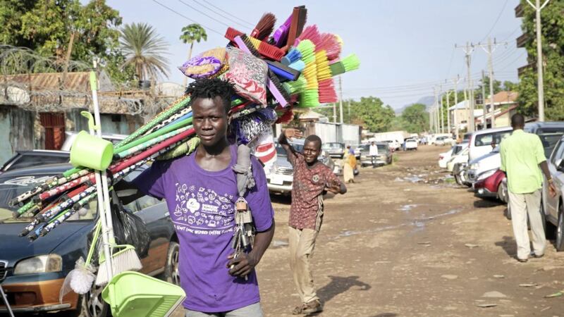 A young merchant carrying brooms to sell walks along a street after the recent ousting of Sudan&#39;s President Omar al-Bashir, in the capital Juba, South Sudan. Picture by Sam Mednick/AP 