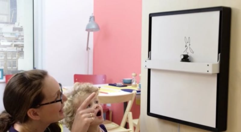 A little girl watches a drawing appear