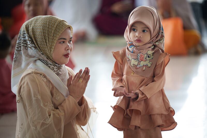 A Muslim woman shows her daughter how to pray as they attend a mosque in Kuala Lumpur, Malaysia (Vincent Thian/AP)