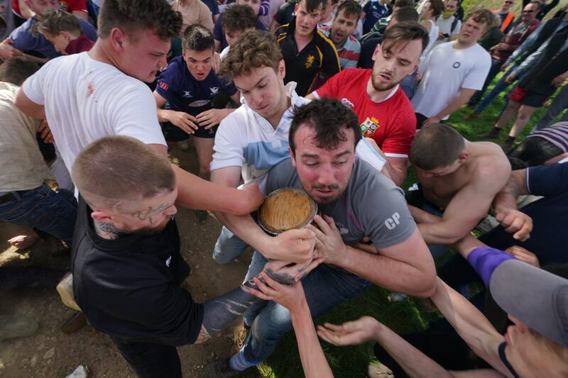 Players pass the ‘bottle’, an old field barrel holding about a gallon of beer during the traditional game of bottle-kicking, played on Easter Monday between the neighbouring villages of Hallaton and Medbourne in Leicestershire