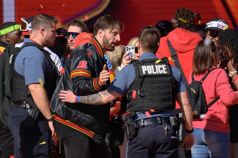 Police escort Kansas City Chiefs tight end Noah Gray and his teammates off the stage after a shooting following their victory parade and rally in Kansas City (AP Photo/Reed Hoffmann)
