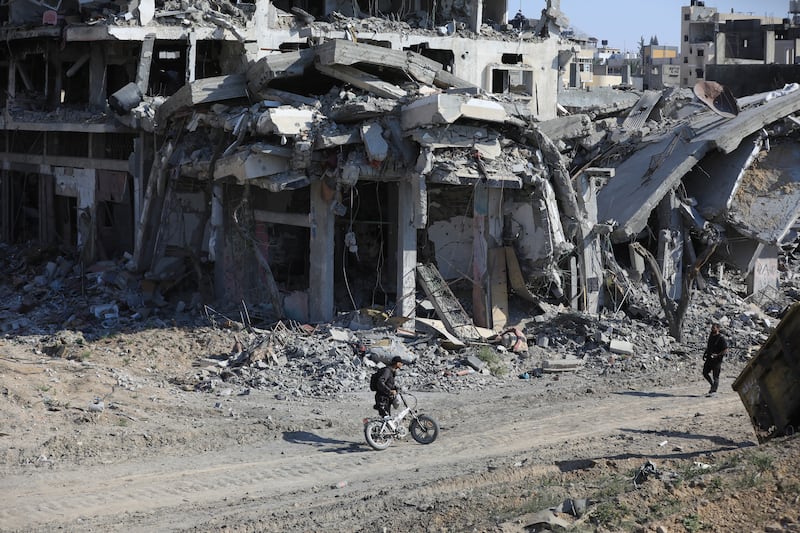 Palestinians walk through the destruction left by the Israeli air and ground offensive after they withdrew from Khan Younis, southern Gaza Strip (Ismael Abu Dayyah/AP)