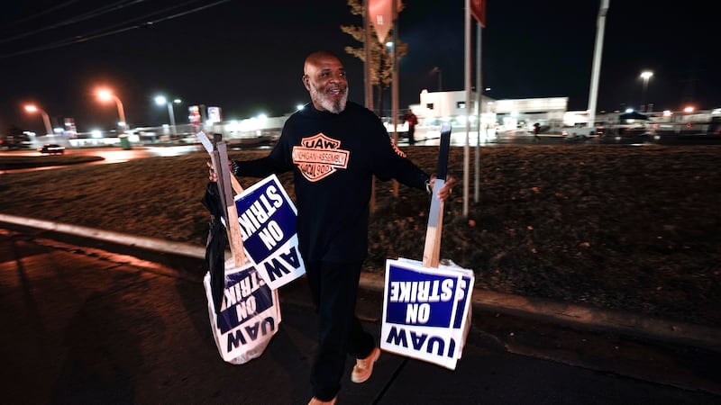 United Auto Workers member Marcel Edwards carries On Strike signs from the picket line to Local 900 headquarters at the Ford Michigan Assembly Plant in Wayne, Michigan (Paul Sancya/AP)