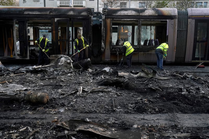 Debris is cleared from a burned-out Luas and bus on O’Connell Street in Dublin