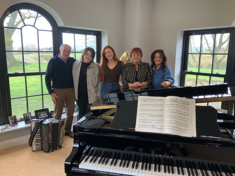 Susan McCann pictured beside a grand piano with husband Dennis, daughter Linda and granddaughters Sinéad and Laura, who all appear on her new album After All This Time