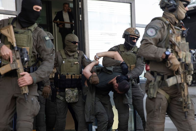 Kosovo police officers from the Special Intervention Unit escort one of the arrested Serb gunmen out of court 