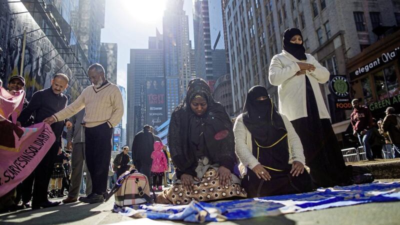 Women pray as two men check a flag during a rally in support of Muslim Americans and protest of President Donald Trump&#39;s immigration policies in Times Square, New York Picture by Andres Kudacki/AP 